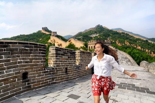 Happy cheerful joyful tourist woman at Great Wall of china having fun on travel smiling laughing and dancing during vacation trip in Asia. Girl visiting and sightseeing Chinese destination in Badaling