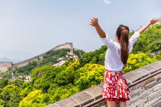 Carefree woman tourist with arms up on Great Wall of china having fun at famous Badaling attraction during travel vacation in Beijing. Winning, success, freedom trousim concept.