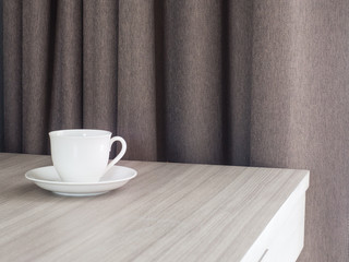 A cup of coffee and notebook on wood table . Coffee break in morning ,break working  / selective focus.Blank seating  indoor in living room .copy space for create idea for business.