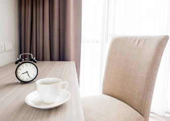 A cup of coffee and notebook on wood table . Coffee break in morning ,break working  / selective focus.Blank seating  indoor in living room .copy space for create idea for business.