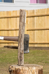 axe splitting camp fire wood on a stump.