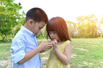 Little asian boy and girl use the smart phone for playing a game on the internet.