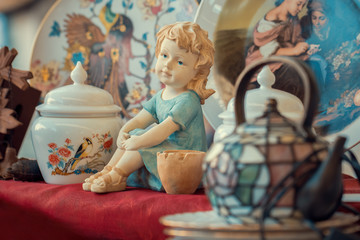 ceramic girl figurine and porcelain vase in sunday flea market. Antique bazaar