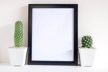 succulents or cactus in concrete pots over white background on the shelf and mock up frame photo