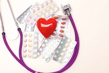 Close up of pills spread over the table with stethoscope and heart lying beside