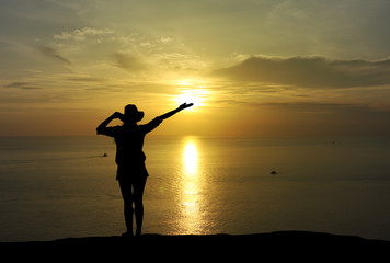 Silhouette of woman raising hands at sunset