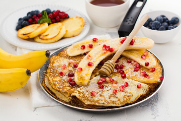 Sweet crepes with banana, honey and pomegranate seeds