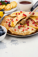 Sweet crepes with banana, honey and pomegranate seeds