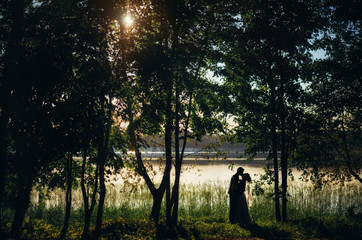 Close-up of beautiful emotional bride young woman holding face of handsome groom young man. Silhouettes of newlywed couple looking into each other eyes, family portrait