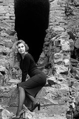 Beautiful sexy and elegant thin young light blonde european woman in total black dress and heels around old ruins in vintage style have a secret in her soul and finding the answer