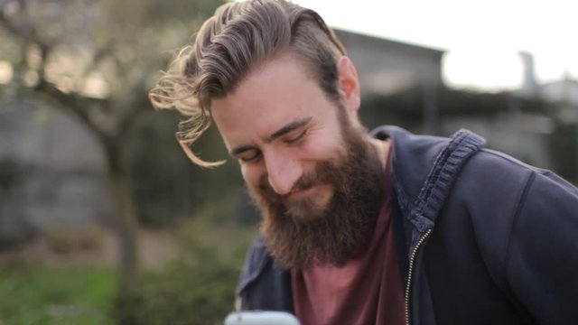 Young bearded caucasian man chatting on the phone, smiling