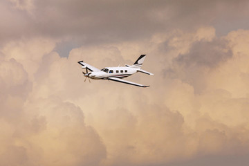 Single turboprop aircraft.. Small private plane flying in blue clouds.
