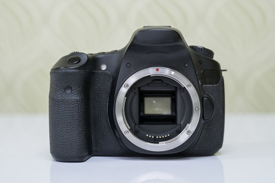 Front view of dslr camera without lens on white table. 
Close up of electronic circuit, rear glass and mount with copyspace in foreground.