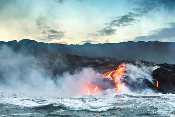 Molten lava flowing into the Pacific Ocean on Big Island of Hawaii at sunrise