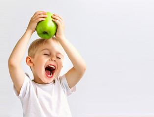small boy holds a big green apple, healthy food and vitamins, smiling, white background, soft focus