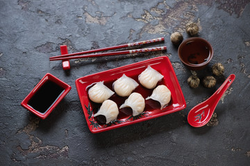 Steamed dim sums with prawns, soy sauce and tea on a brown stone background, studio shot