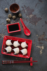 Prawn hargows with soy sauce and green tea over dark brown stone background, vertical shot, top view