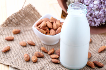 Almond milk in glass bottle on wood background