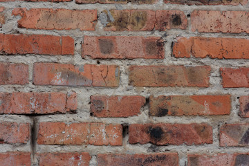 The texture of the background. An old wall of red cracked brick and cement with uneven masonry.