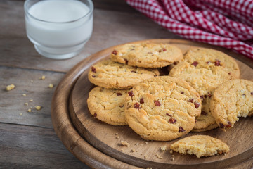 Raspberry cookies on wooden plate and milk glass.