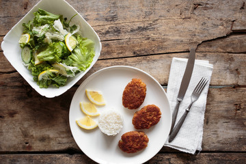 Overhead view of fish crocuettes with fresh green salad.