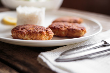 Three fish breadcrumbed cutlet on white plate with rice. Restaurant menu background