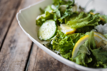 Fresh salad in white bowl on wooden background. Close up image of healthy food