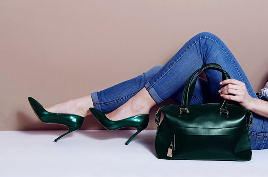 Close up fashion woman legs in green high heels and big bag