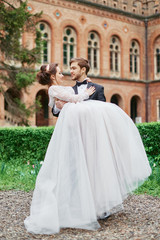 Fototapeta premium Groom carrying bride in park