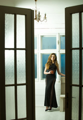 Fototapeta na wymiar Pretty girl in black dress through open doors