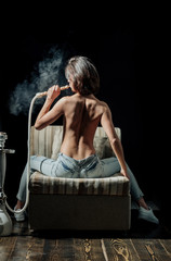 sexy girl with naked body smoking hookah in jeans