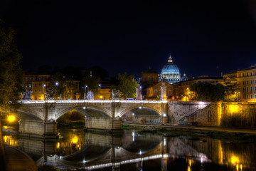 Fototapeta na wymiar Die Brücke Ponte Vittorio Emanuele II mit dem Petersdom im Hintergrund in Rom bei Nacht.The bridge Ponte Vittorio Emanuele II with St. Peter's Basilica in the background in Rome at night.