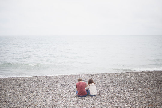 couple sitting on the rocks by the sea and back nature of summer