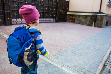A boy with a backpack walking across the street.
