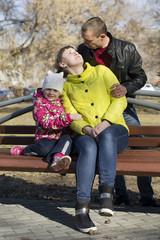 The happy family sits on a bench in the park.