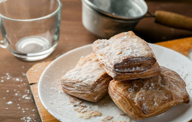 Naklejka premium Few puff pastries in a white plate on a wooden table