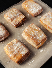 Rows of puff pastry cookies dusted with powdered sugar, vertical