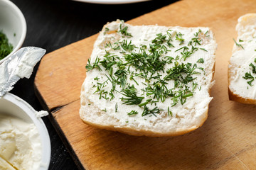 Piece of white bread covered with curd cheese and sprinkled with fresh green dill, selective focus