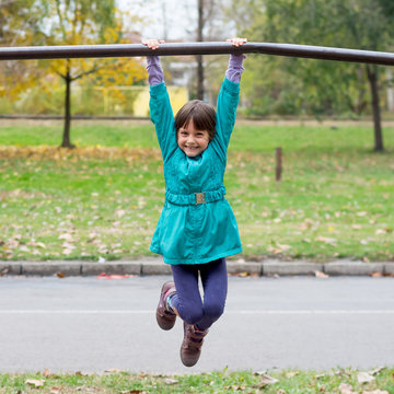 Little girl having fun on playground gymnastics bar