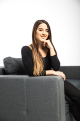 Obraz premium Portrait of happy young woman sitting on sofa on white background