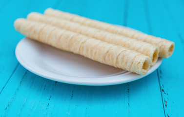 side view sweet egg rolls on dish on blue