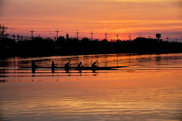 Team work of young men in a row boat silhouetted at sunset © Prin
