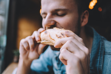Young man sitting in a restaurant and eating a hamburger