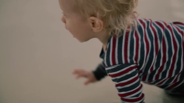 Little baby boy with a toy crawling at the beach