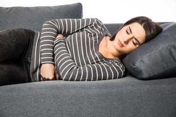 Closeup on pills pack in hand of ill young woman laying on sofa