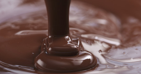 Slow motion of premium dark melted chocolate being poured from spoon in center part of frame, 4k photo