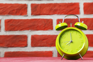 Green alarm clock on the brick wall background