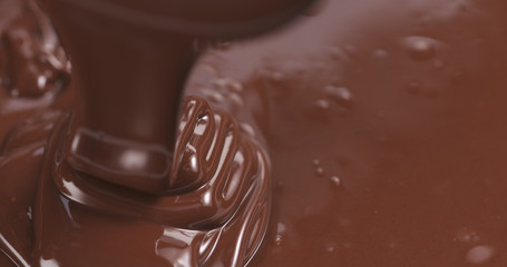 Slow motion of premium dark melted chocolate being poured from spoon in left part of frame, 4k photo