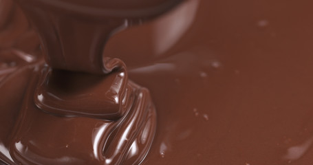 Slow motion of premium dark melted chocolate being poured from spoon in left part of frame, 4k photo