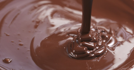 Slow motion of premium dark melted chocolate being poured from spoon in right part of frame, 4k photo